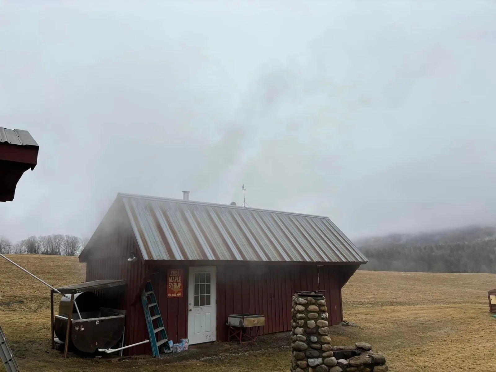 The red sugarhouse in morning mist, sap tank outside