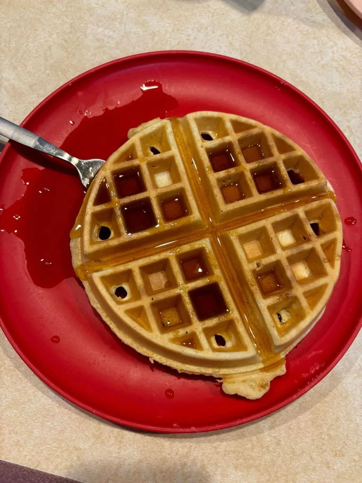 A waffle drizzled with maple syrup
